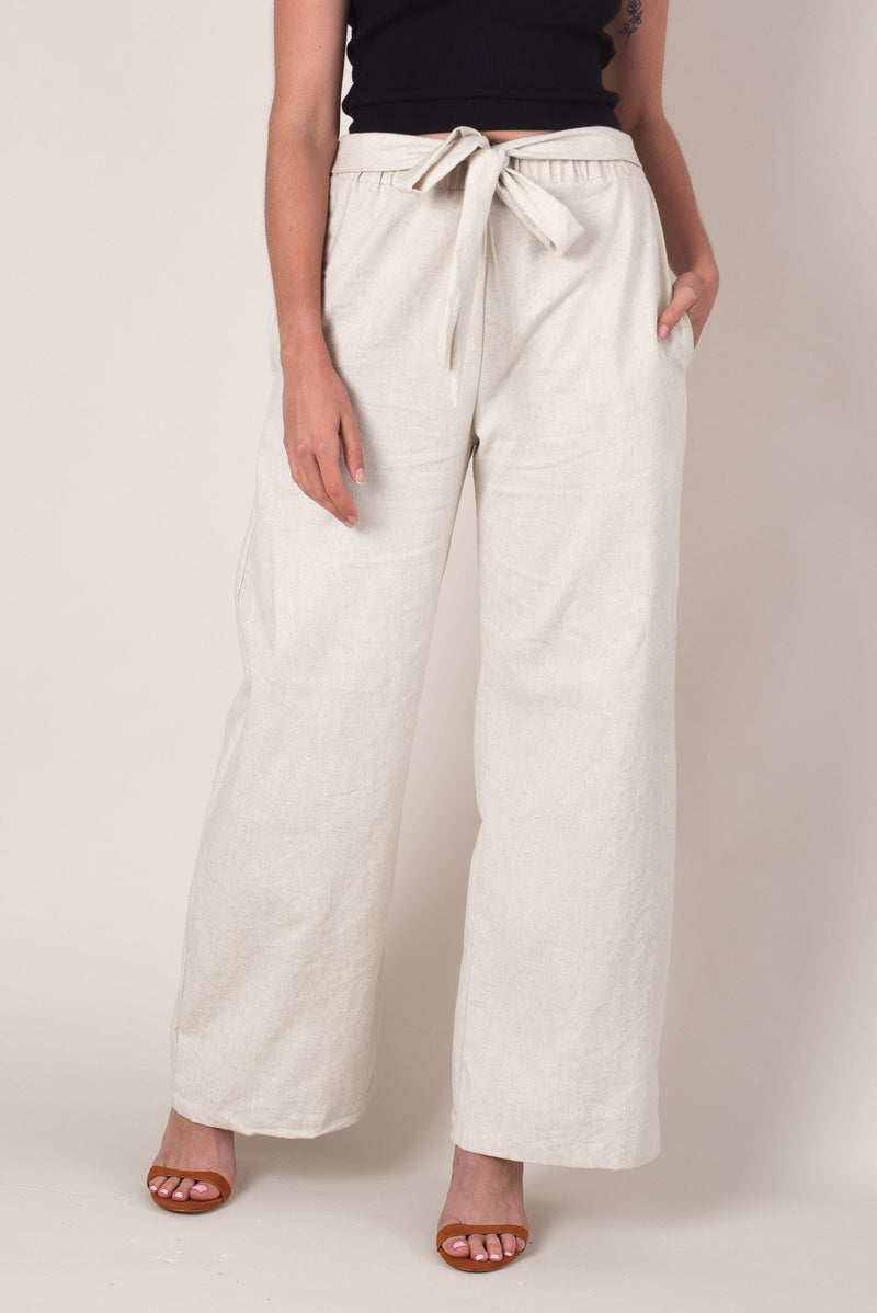 A front close up look the the cream colored wide leg sothea pants, these fair fashion trousers feature two deep pockets, a flattering front tie and a comfortable elastic waist. 